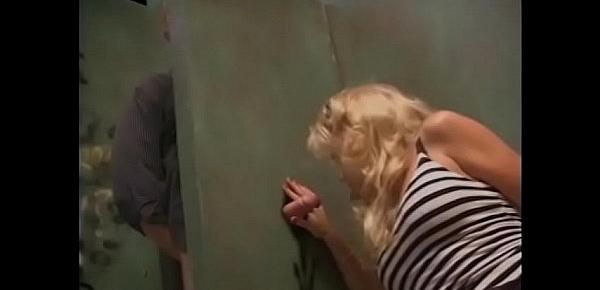  Horny blonde gives a blowjob to a guy from a neighboring toilet cubicle through a hole in the wall